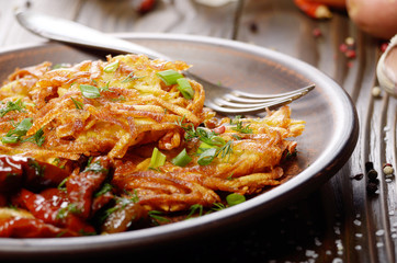 Closeup view at Homemade tasty potato pancakes in clay dish with sun-dried tomatoes