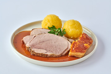 Deutscher Schweinebraten mit Kruste und Knödel auf weißem Hintergrund 