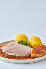 Deutscher Schweinebraten mit Kruste und Knödel auf weißem Hintergrund 