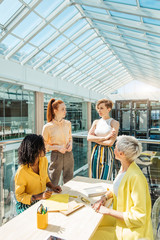 confident eader of team with crossed arms listening to the suggestions of her colleagues in the office room