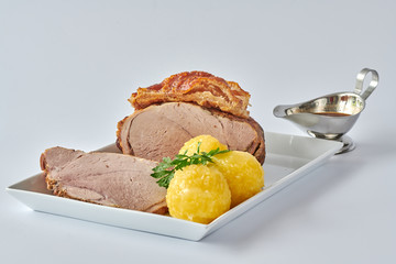 Deutscher Schweinebraten mit Kruste und Knödel auf weißem Hintergrund 