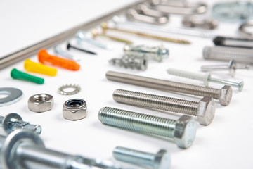 An assortment of carpenters material like screws, bolts, fixings, nuts screws and nails on a white background. - obrazy, fototapety, plakaty
