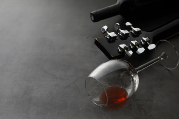 Guitar and high glass with red wine on a stone background.