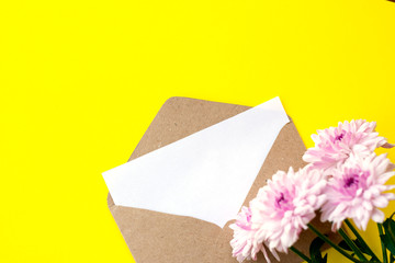 Love envelope with blank letter and pink chrysanthemum flowers on bright yellow bacground. Copy space
