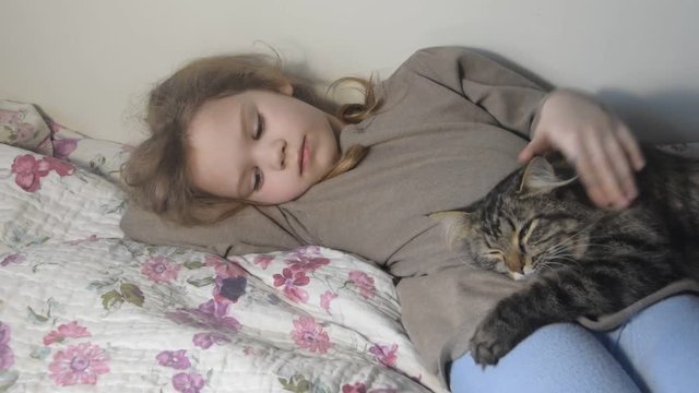 a on the bed sits a girl with a gentle fluffy cat