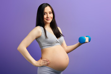 Beautiful asian pregnant woman keeping good fit at third trimester doing exercise using dumbell on...