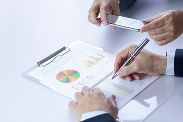 Two businessmen or analysts taking a photograph while reviewing financial statement report on...
