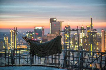 Urban Explorer sleeping in a hammock over the roofs of Frankfurt am Main