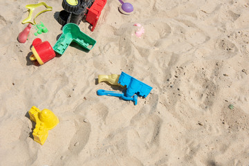 Colourful plastic toys with various shapes and kinds left unattended on a sand box in a resort, waiting for kids to come and enjoy them in a morning.