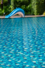 Swimming pool in a hotel with a dolphin slider on the pool side With clear and clean blue good looking and reflecting water in the morning.