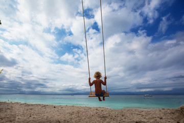 The back of the boys Swings are playing on the beach