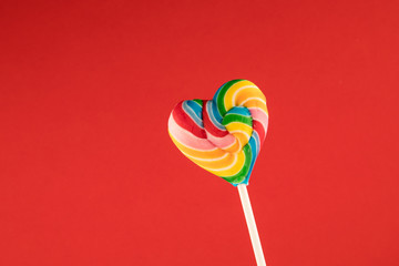 Lollipop, Big Heart shaped Rainbow colored lollipop isolated on valentine Red background, copy space