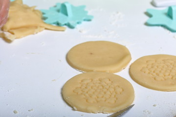 Round blanks from rolled dough with an ornament. For making marshmallow sandwiches. They lie on the table along with the cooking tools.