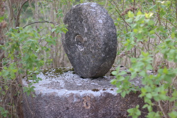 Old abandoned sculpture in the form of a rounded stone covered with moss. Close-up