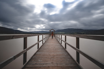 Fototapeta premium Drewniany most przez jezioro w pochmurny dzień długi czas ekspozycji