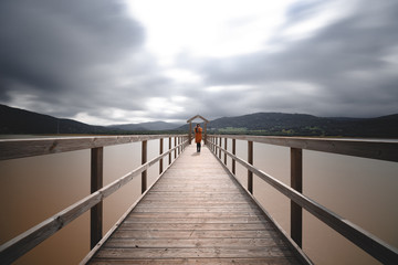 Wooden bridge across lake on cloudy day long exposure