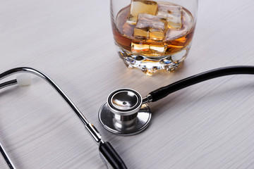 Medical concept - Stethoscope and glass with cognac. Alcoholism
