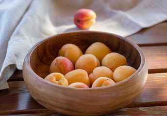 The ripe apricots, juicy fresh yellow with red outflow, which grew on the Azerbaijani earth in a wooden cup in beams of the sunset sun. Macro.