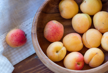 The ripe apricots, juicy fresh yellow with red outflow, which grew on the Azerbaijani earth in a wooden cup in beams of the sunset sun. Macro.