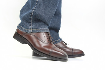 Men's legs in jeans shod in classic brown shoes
