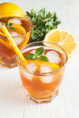 Refreshing citrus lemonade, summer drink. Ice tea with fresh lemon and mint on wooden background. Refreshment beverage concept.