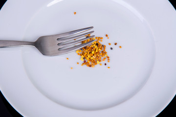 fork with white plate with pollen from bees to eat
