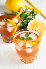 Refreshing citrus lemonade, summer drink. Ice tea with fresh lemon and mint on wooden background. Refreshment beverage concept.