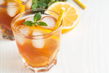 Refreshing citrus lemonade, summer drink. Ice tea with fresh lemon and mint on wooden background. Refreshment beverage concept.