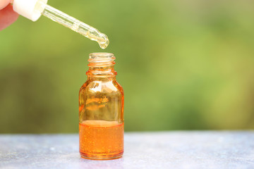 Vitamin C, Orange oil dropping to glass bottles on natural green background