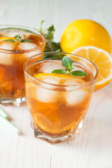 Refreshing citrus lemonade, summer drink. Ice tea with fresh lemon and mint on wooden background. Refreshment beverage concept.