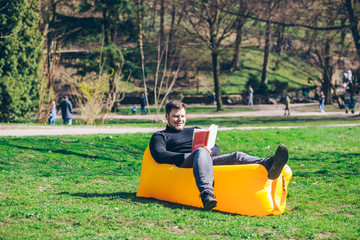 book reading concept. man in city park on inflatable mattress
