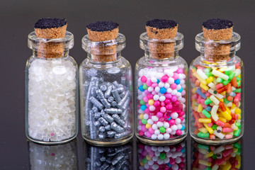 four glass bottles filled with colorful candy and for cake decoration