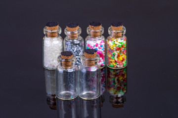 four glass bottles filled with colorful candy and for cake decoration
