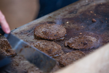 Chef grilling appetising beef burgers outdoors on open kitchen at music festival event