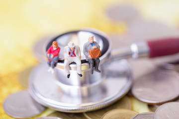 Obraz na płótnie Canvas Miniature people: Elderly people sitting on stethoscope. Retirement planning. money saving and Investment. Time counting down for retirement concept.