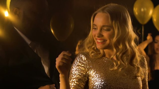 Beautiful mixed-race couple enjoying party, dancing under falling confetti