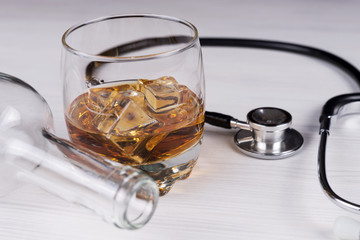 Alcoholism. Stethoscope, glass with cognac an empty bottle. Medical concept