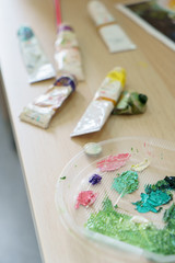 Painter equipement easel oil colours are lying on table workspace, foreground palette
