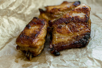 Pieces of roasted barbecue on wrapping paper. Close-up.
