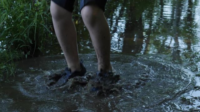 kid walking and jumping in a forest mud puddle