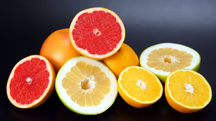 Citrus fruit. Cut orange, lemon and grapefruit on dark background