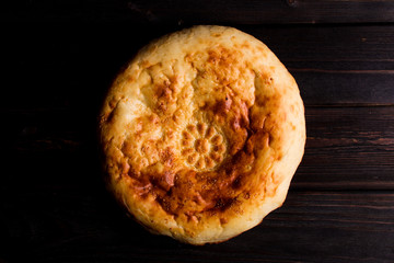 Traditional bread pita on the dark wood table with herbs and garlic. Homemade baking recipe. Top view. Menu.