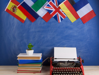 Political, news and education concept - red typewriter, flags of Spain, France, Great Britain and other countries, books