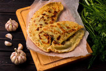 Baker making traditional dish of Armenians (Zhengyalav hatz, Zhangyalov hats) is a type of flatbread stuffed with finely diced herbs and green vegetables. Homemade recipe. Top view and horizontal.