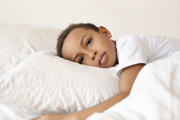 Sadness and loneliness concept. Portrait of sad or thoughtful pensive Afro American male child in...