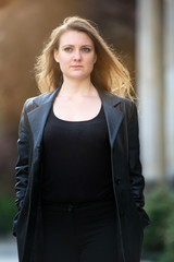 young brunette woman in leather jacket standing outside