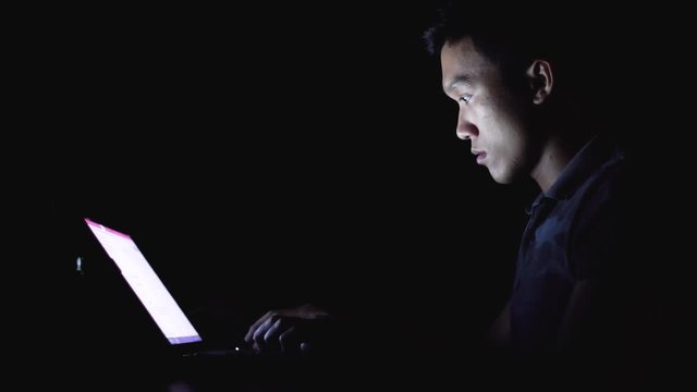 Young programer student run assignment with laptop alone at midnight in the dark room