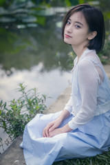 A young Chinese girl sits besides the lake