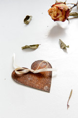 Symbol der Liebe: rostiges Herz, Blätter und getrocknete Rose vor weißem Hintergrund