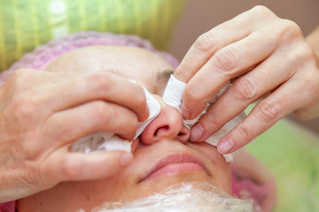 A young girl is lying on a couch during cosmetic procedures with a mask on the face above which...